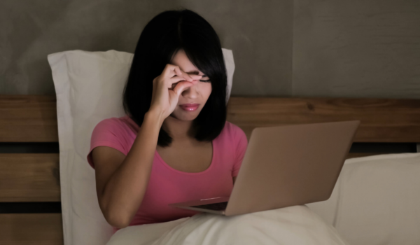 fille qui est devant son écran d'ordinateur le soir et qui se frotte les yeux