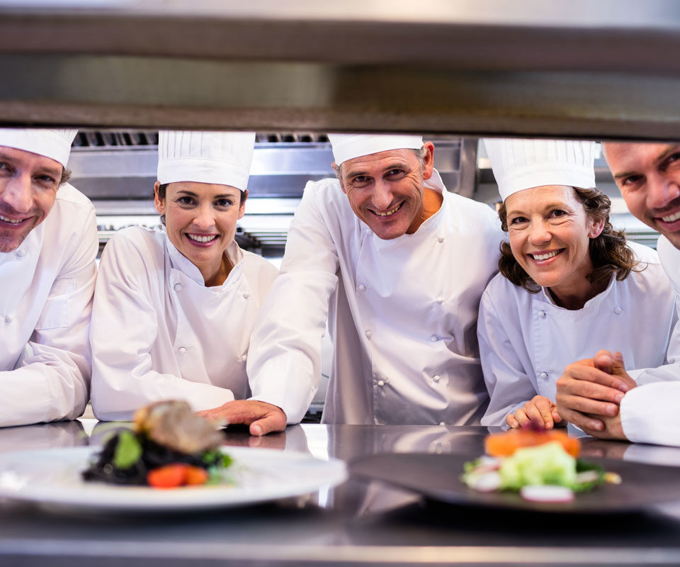 Chefs cuisiniers souriants devant des assiettes préparées par Culinoa, client de l'agence web Poush