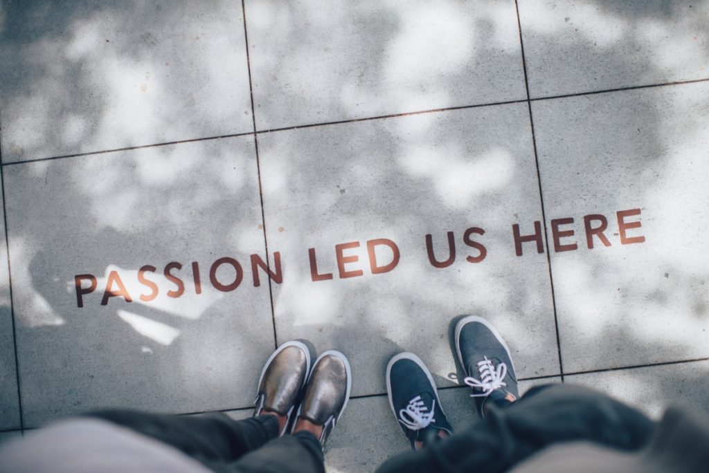 deux personnes se tiennent devant une inscription au sol disant "passion led us here"