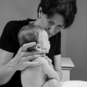 Femme qui maintient un bébé en position assise