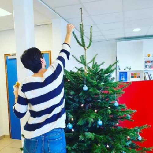 Une personne décore le sapin avec des boules de Noël