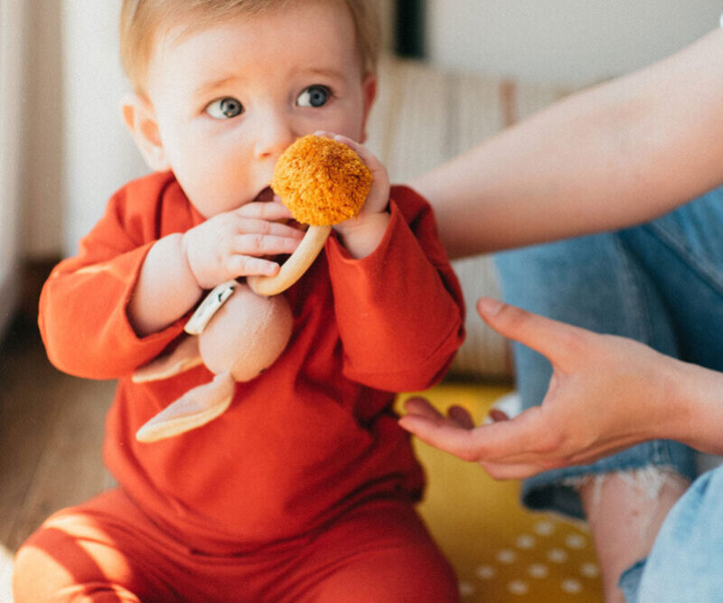 pop kidz modele bebe Un bébé qui porte les vêtements de la marque Pop Kidz et qui a un doudou dans ses mains