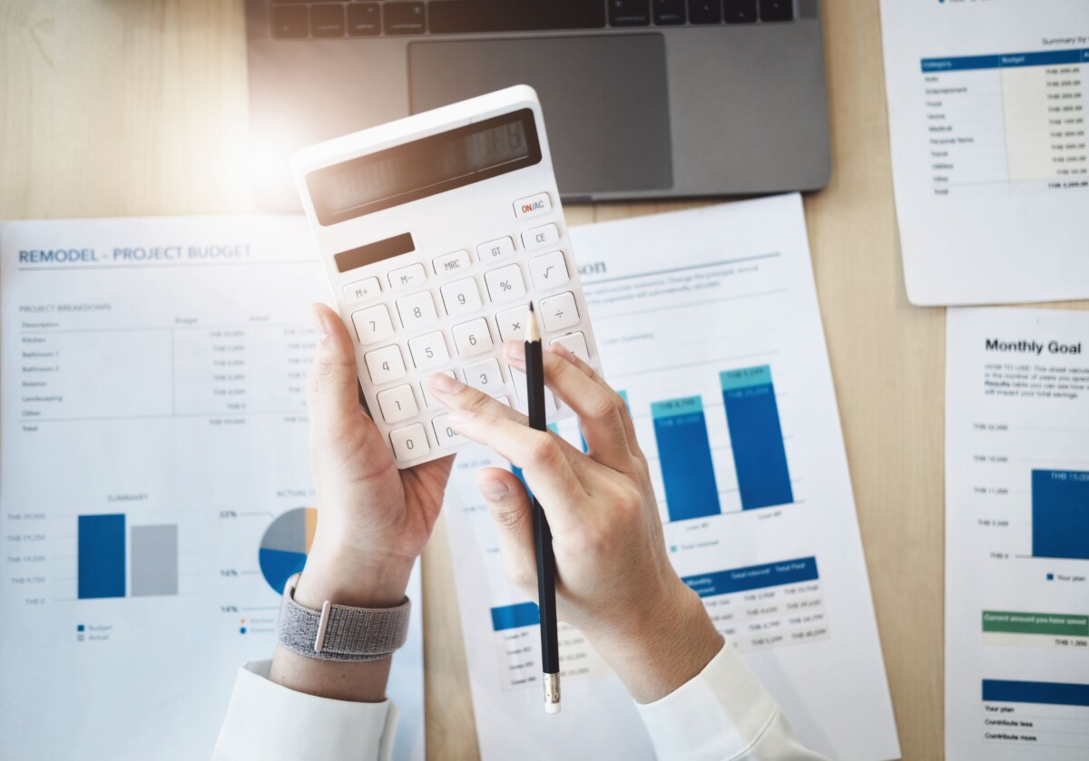 Mains qui tiennent une calculette avec des feuilles à l'arrière