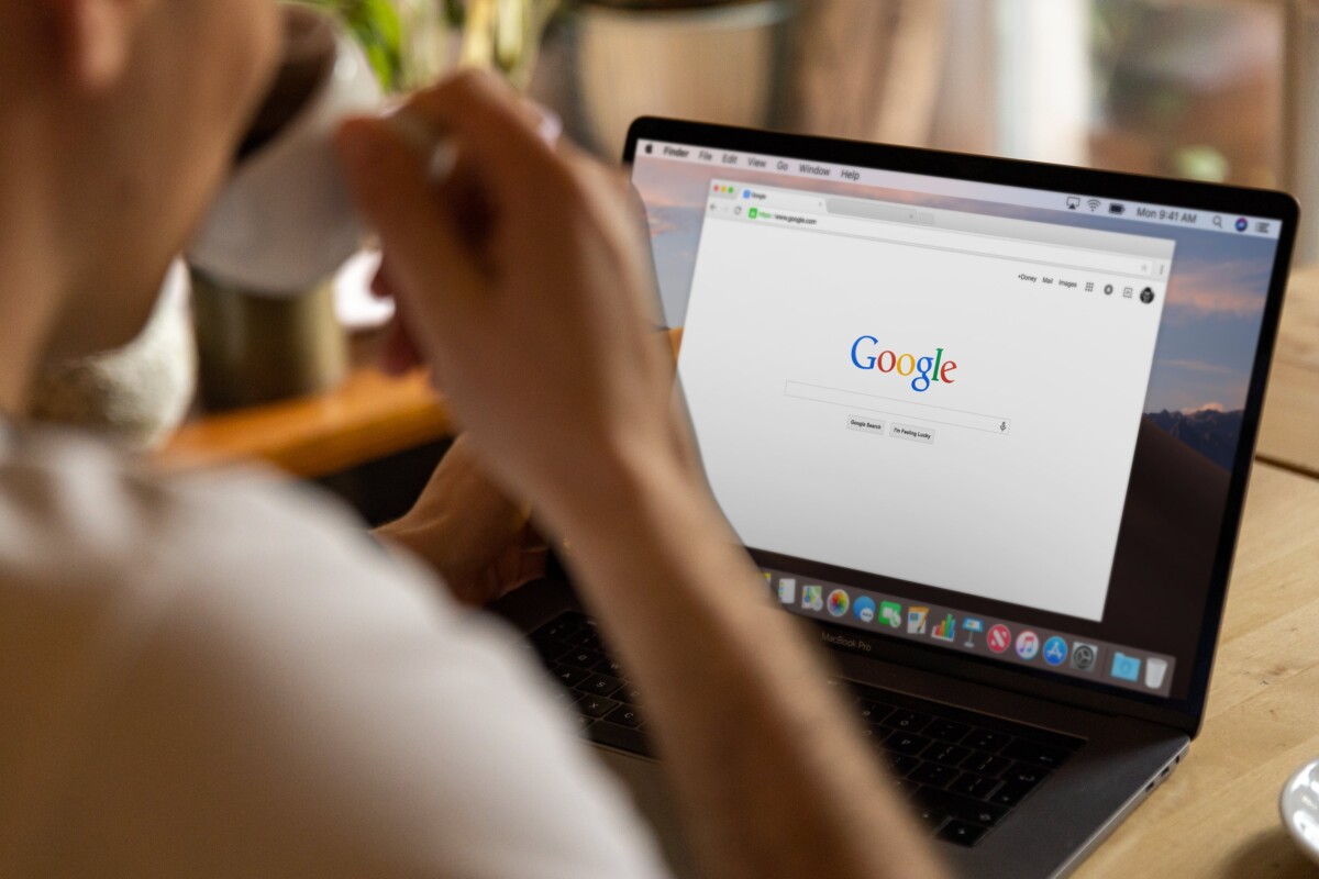 Homme qui boit un café devant un ordinateur portable ouvert avec Google