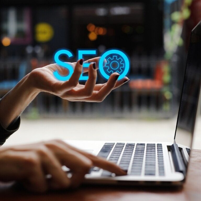Femme devant un ordinateur portable qui tient dans sa main gauche les lettres SEO en bleu