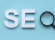 Lettre S et E sur fond bleu avec un loupe noire pour former le mot SEO