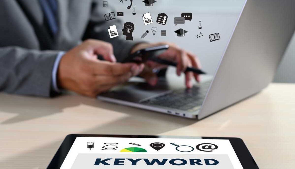 Un homme utilise son smartphone et son ordinateur portable, entouré d'icônes de communication et d'éducation. À côté, une tablette affiche 'KEYWORD' avec des icônes de recherche et gestion.