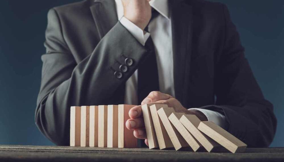 Crise Homme en costume arrête la chute de dominos en bois pour symboliser la gestion de crise pour protéger l'image de marque